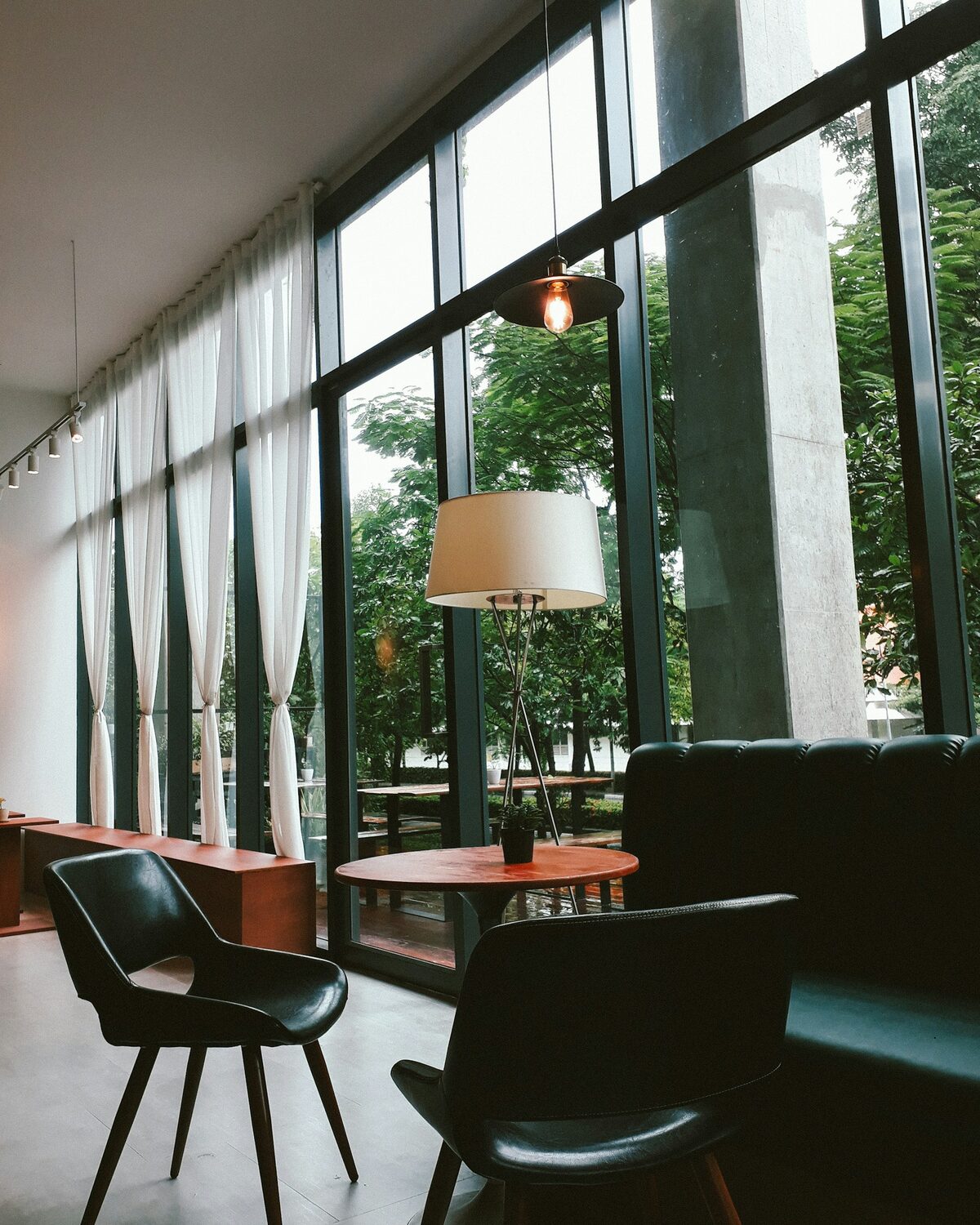 Bright lounge with chairs, a floor lamp and floor-to-ceiling windows